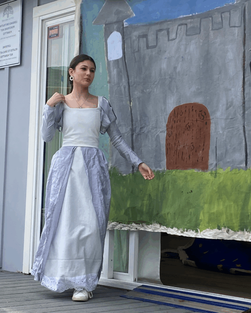 Student dressed up in a princess gown in front of canvas backdrop with a castle